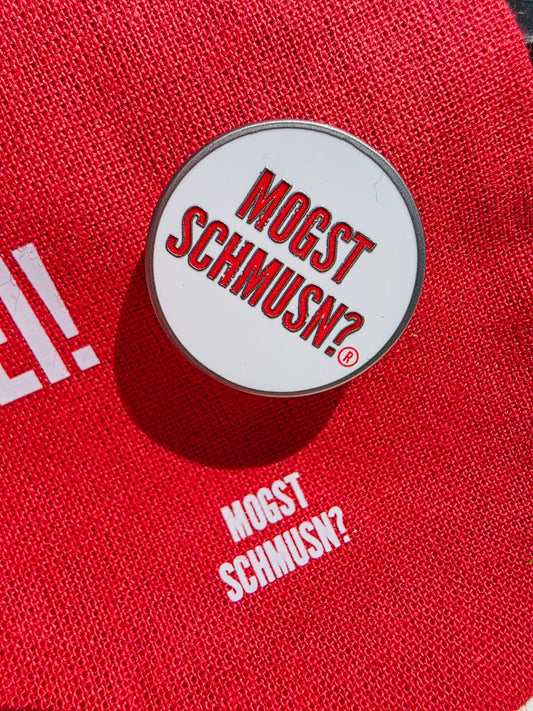 MOGST SCHMUSN?® PIN in Markenrot mit Premium Butterfly-Verschluss auf einem roten Baumwolluntergrund