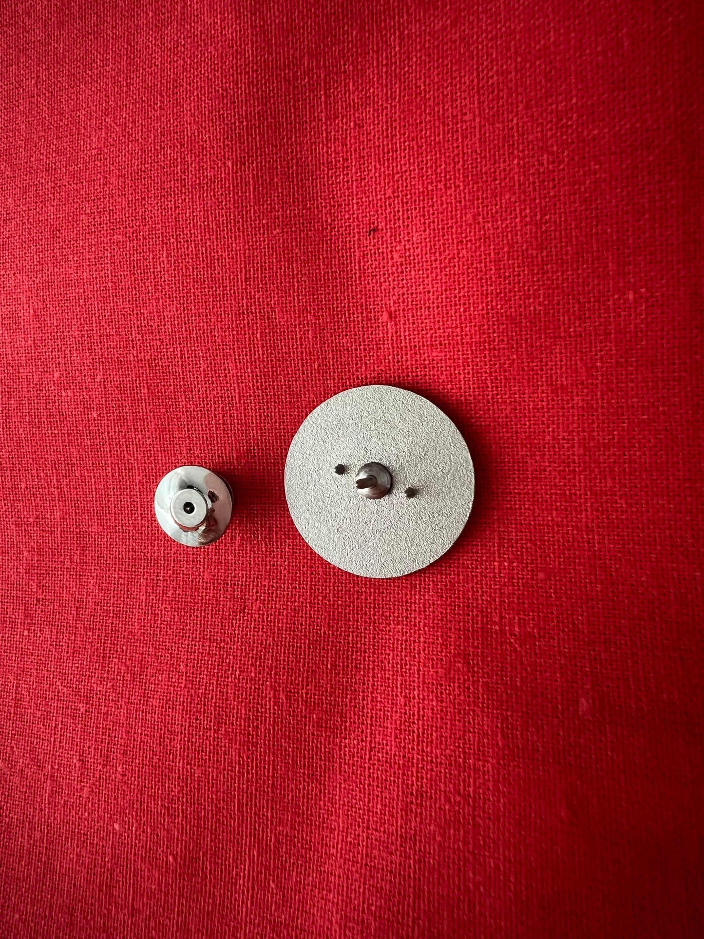 MOGST SCHMUSN?® PIN in Markenrot mit Premium Butterfly-Verschluss – Detailansicht - Rückseite mit Verschluss auf rotem Baumwolluntergrund dargestellt